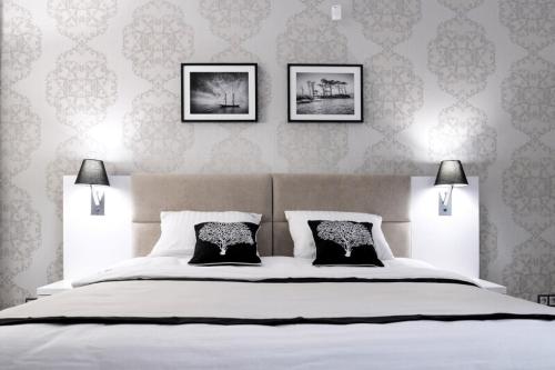 a bedroom with a large white bed with three pictures on the wall at Willa Cicho Sza in Pobierowo