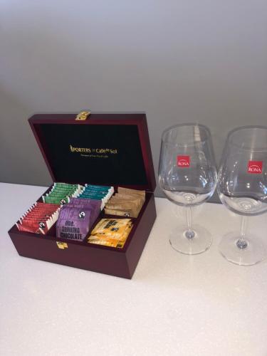 a box of books and two wine glasses on a table at Memorial holiday home in Christchurch