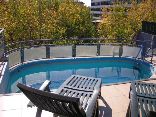 a swimming pool with two chairs and a table at Apart San Lorenzo in Mendoza