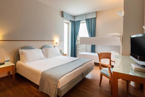 a hotel room with a bed and a flat screen tv at Hotel Baia Flaminia in Pesaro