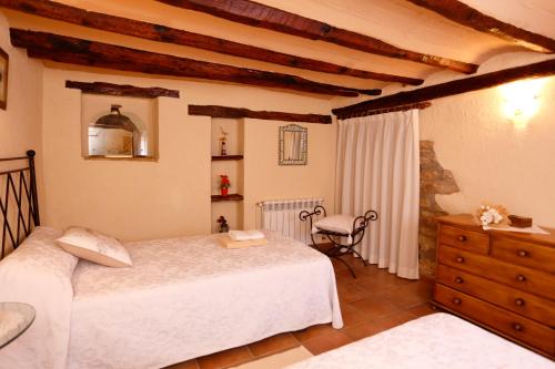 a bedroom with two beds and a dresser at Casa Rural Mas de Sant Pau - Turistrat. in Albocácer