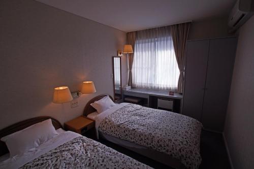 a hotel room with two beds and a window at Pension Entre - deux - Mers in Hachimantai