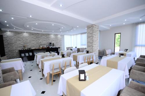 a restaurant with white tables and chairs and a fireplace at Dream Tower in Batumi