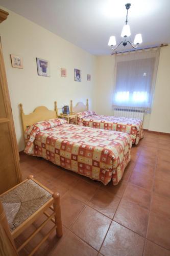 a bedroom with two beds and a table and a chair at Casas Rurales Montemayor in Casas de Lázaro