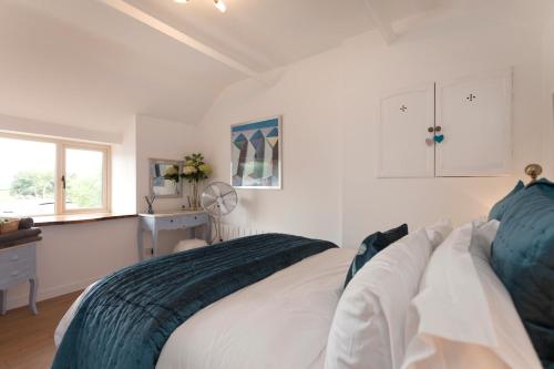 a white bedroom with a bed and a window at Vale View Barn in Grantham