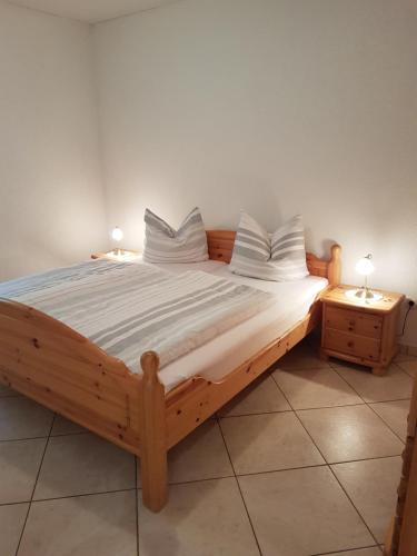 a wooden bed in a room with two night stands at Ehrentaler Ferienhaus GbR in Schmalkalden