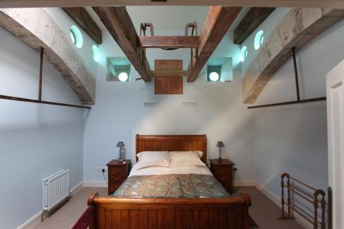 a bedroom with a wooden bed in a room with beams at Kinghorn Town Hall in Kinghorn