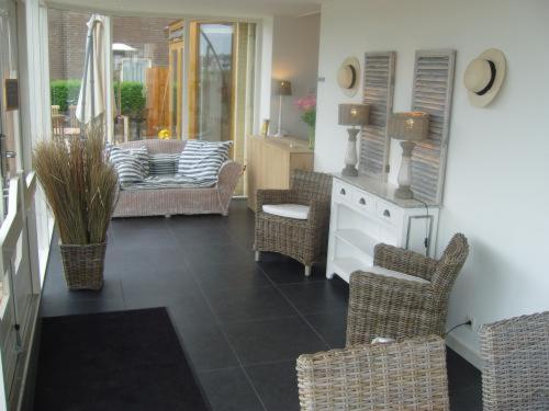 a living room with wicker chairs and a table at Badhotel Zeecroft in Wijk aan Zee