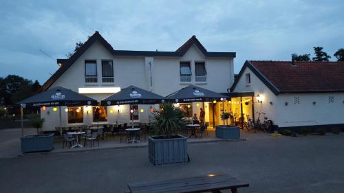 a restaurant with tables and umbrellas in front of a building at De Twentse Nar in De Lutte
