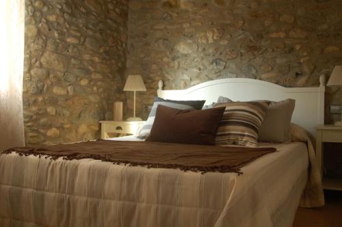 sypialnia z dużym łóżkiem i kamienną ścianą w obiekcie Mas Font w mieście Sant Gregori