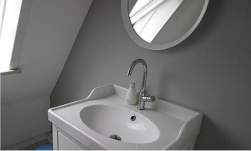a white bathroom with a sink and a mirror at Ferienwohnung am Strandweg in Hohwacht