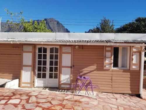 une petite maison avec une chaise violette en face dans l'établissement Le Moutardier 2, à Cilaos