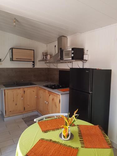 uma cozinha com uma mesa e um frigorífico preto em Le Moutardier 2 em Cilaos