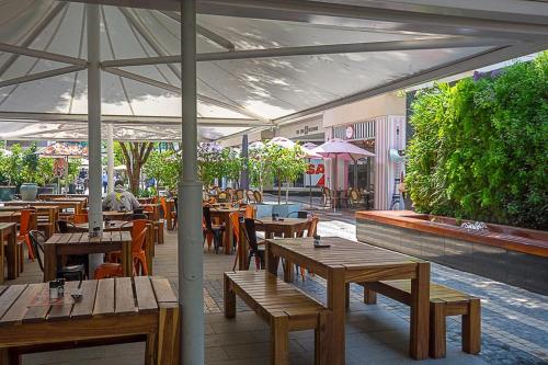 a restaurant with wooden tables and chairs and an umbrella at Hotel Amor Rosebank in Johannesburg