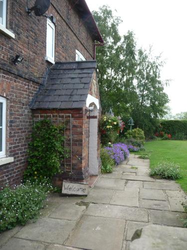 a brick house with a small shed on the side of it at Birtles Farm Bed and Breakfast in Knutsford