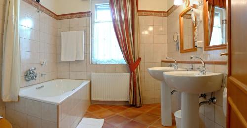 a bathroom with a tub and a sink and a bath tub at Lévay Villa Hotel in Miskolc