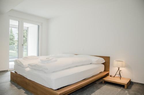 a white bed with a wooden frame in a bedroom at Apartment JungfrauCenter Schynige Platte - GriwaRent AG in Interlaken