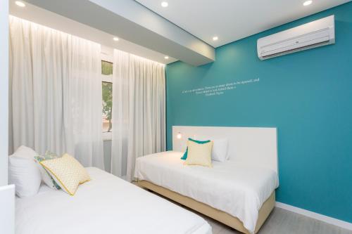 two beds in a room with a blue wall at Chic Studios in Parede