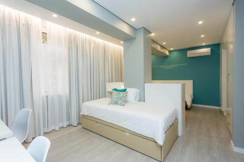 a bedroom with a white bed and a blue wall at Chic Studios in Parede