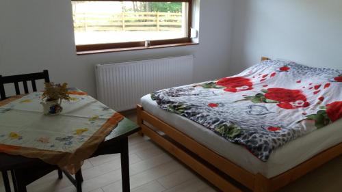 a bedroom with a bed and a table and a window at Dom Wakacyjny Kuszewo in Czaplinek