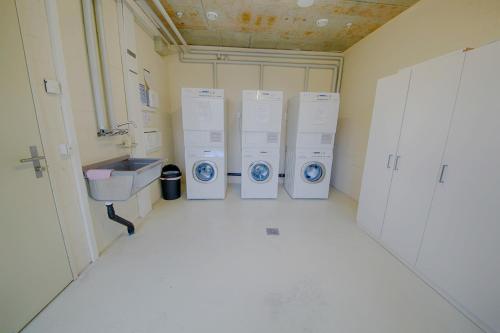 a bathroom with four washing machines and a sink at HITrental Allmend Comfort Apartments in Luzern