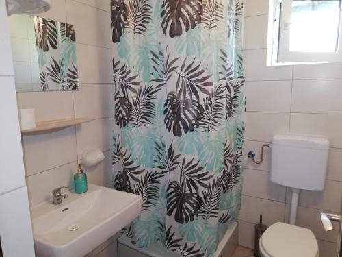 uma casa de banho com um lavatório e uma cortina de chuveiro em Sobe Zimmer Rooms Nika em Tušilović