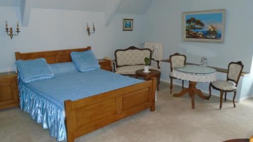 a bedroom with a bed and a table and chairs at Manoir de la Foulerie in Ancteville