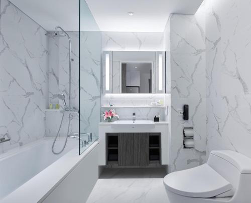 a white bathroom with a sink and a shower at Somerset Maison Asoke in Bangkok