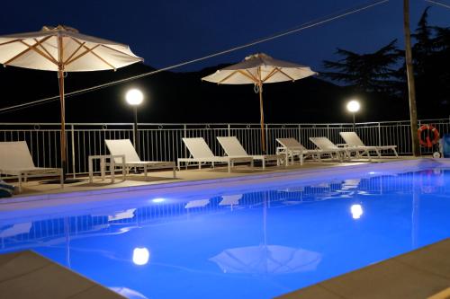 a swimming pool with chairs and umbrellas at night at Albergo Elisa in Comano