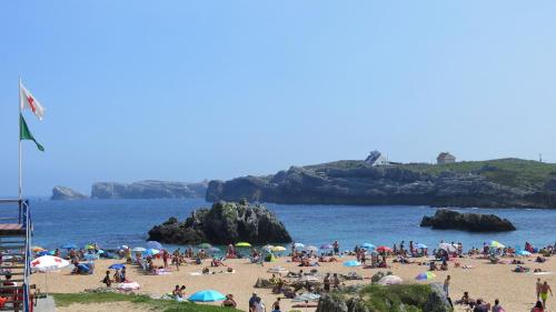 a large group of people on a beach at Apartamentos La Canal in Soto de la Marina