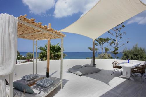 a white patio with a table and a white umbrella at Sigalas Beach Hotel in Kamari
