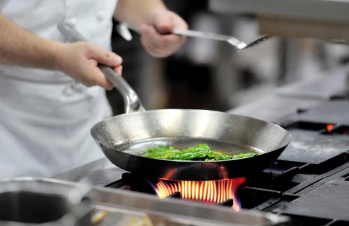 a person cooking food in a wok on a stove at Clanree Hotel & Leisure Centre in Letterkenny