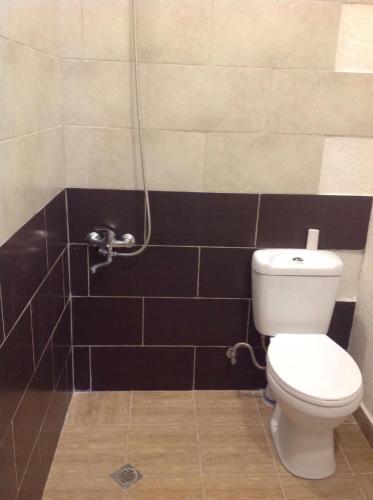 a bathroom with a white toilet and black tiles at L House in Tʼelavi