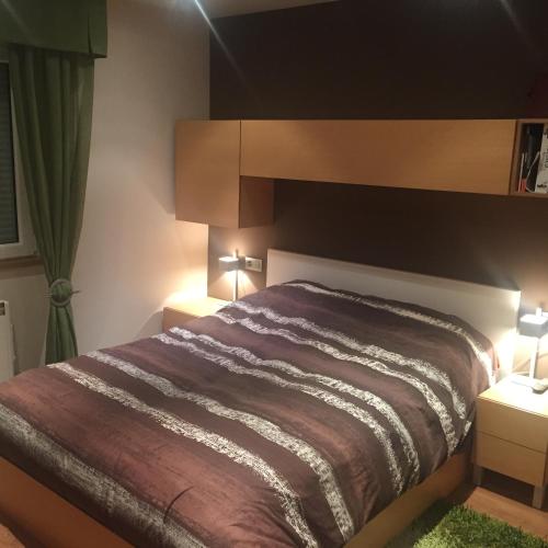 a bedroom with a bed with two night stands and two lamps at Bierzo centro in Ponferrada
