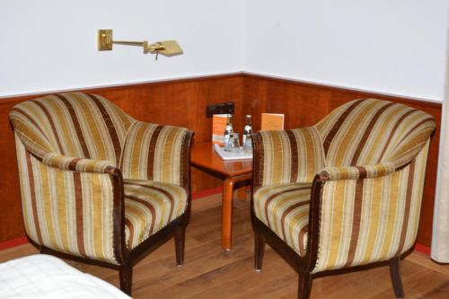 two striped chairs and a table in a room at Villa Widder - Boutiquehotel in Staatsbad Brückenau