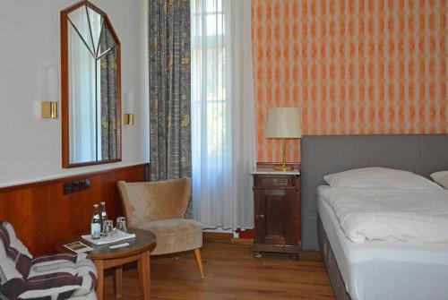 a bedroom with a bed and a table and a chair at Villa Widder - Boutiquehotel in Staatsbad Brückenau