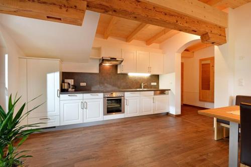 a large kitchen with white cabinets and a wooden floor at Appartement Hinterholzer in Going