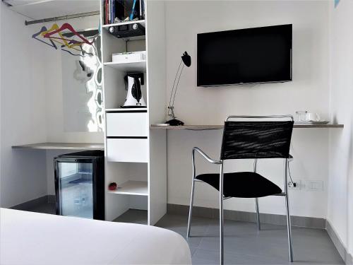 a bedroom with a chair and a tv on a wall at VIA DEL MARE | BED & BREAKFAST in Lamezia Terme