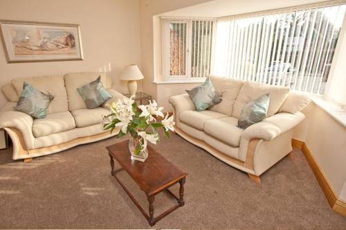 a living room with two couches and a table with flowers at Holly Lodge in Alnwick