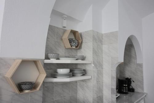 a kitchen with white walls and shelves with plates at Sigalas Beach Hotel in Kamari