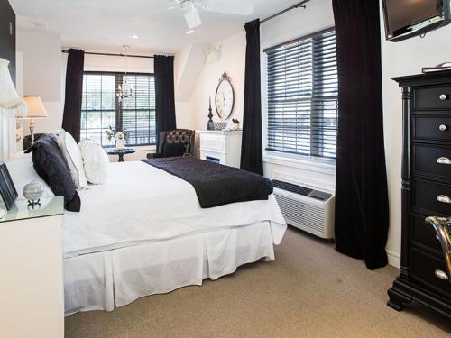 a bedroom with a white bed and a desk and window at Inn on the Harbour and Telegraph House in Port Stanley