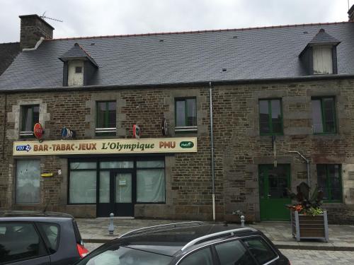 un bâtiment en briques avec des voitures garées devant lui dans l'établissement CHAMBRES / BEDROOM, à Pleine-Fougères
