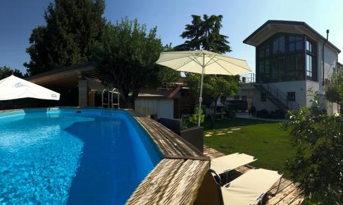 a swimming pool with an umbrella and chairs and a house at Su Misura in Molini