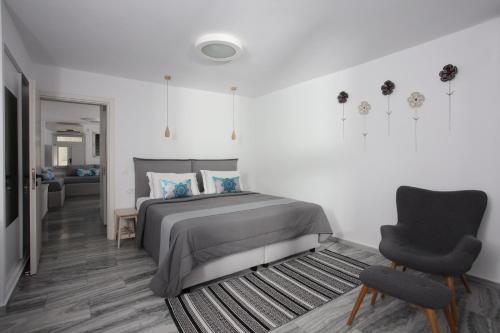 a white bedroom with a bed and a chair at Sigalas Beach Hotel in Kamari