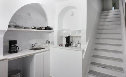 a white kitchen with a sink and a staircase at Sigalas Beach Hotel in Kamari