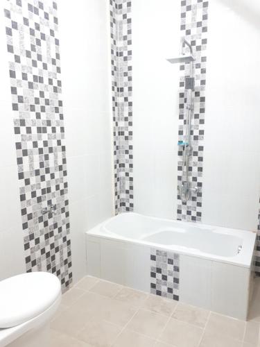 a white bathroom with a tub and a toilet at Villa Fifari - 5 Kamar Tidur, 3 Kamar Mandi in Batu