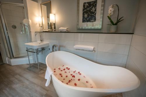 a bathroom with a bath tub and a sink at Hogarths Stone Manor in Kidderminster