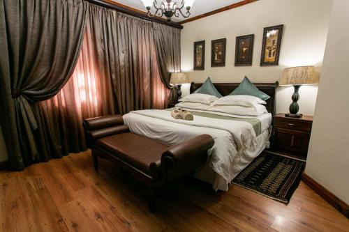 a bedroom with a large bed and a leather chair at Royl Court Guesthouse in Kimberley