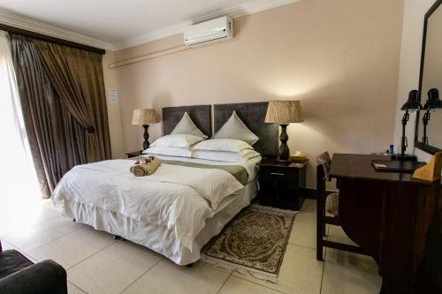 a bedroom with a bed with a teddy bear on it at Royl Court Guesthouse in Kimberley