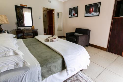 a bedroom with two beds and a chair at Royl Court Guesthouse in Kimberley